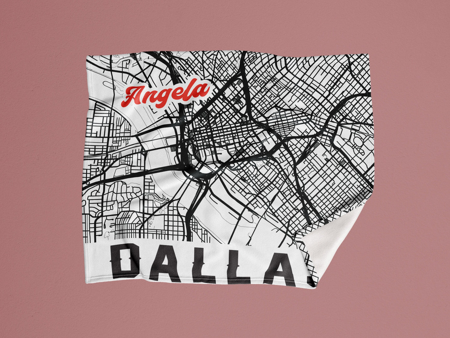 A white blanket in a pink background with personalized city map of dallas and name