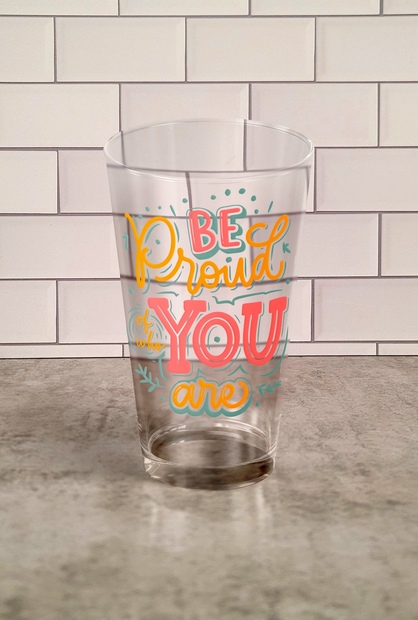Be Proud Of Who You Are transparent Tumbler Glass against a slipslap wall