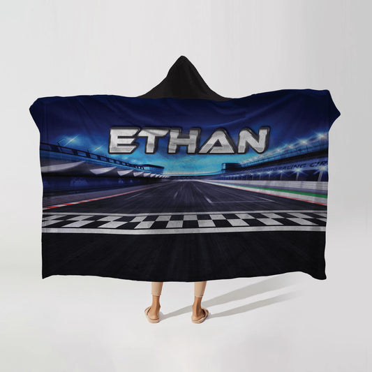 Person wearing a hooded fleece blanket with a race track design, featuring the name "Ethan" in bold letters