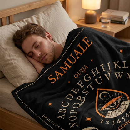 Person wrapped in ouija board throw blanket as spooky Halloween seasonal gift
