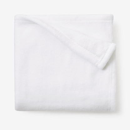 Folded white fleece blanket on a white surface