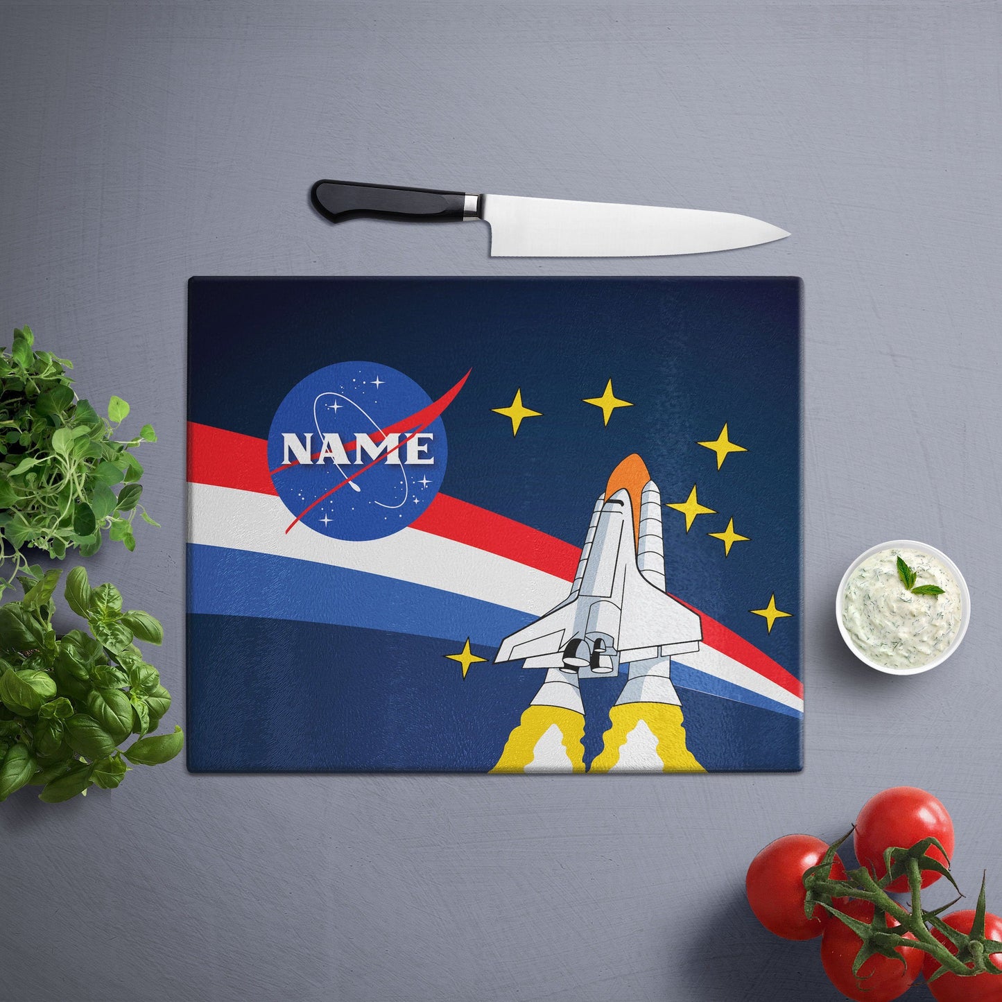 A glass cutting board with a lost in space design on a white wooden surface and knife on side