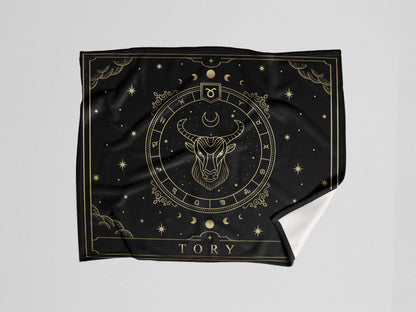 A black throw wooven blanket with Taurus Zodiac sign and customized name with a white background